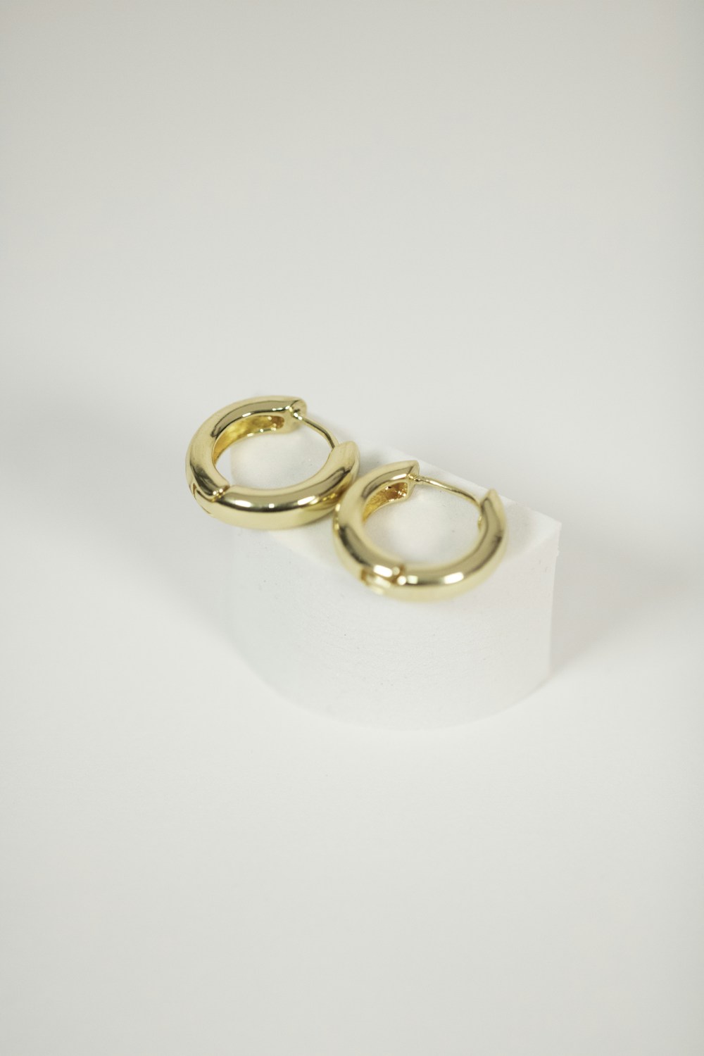 Minimal gold hoops on an ivory plinth